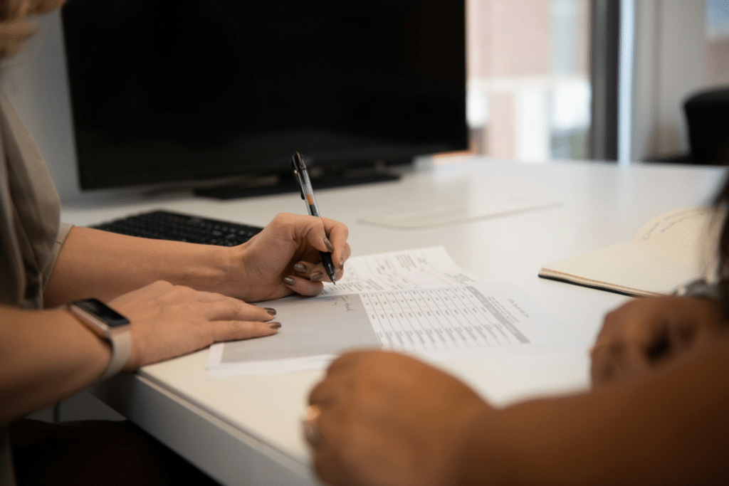 Deux personnes remplissent un questionnaire d'évaluation fournisseur sur un bureau, stylo en main
